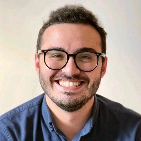 Artur Batissoco, fundador da Elixir Fragrância, sorrindo, de óculos e camisa azul
